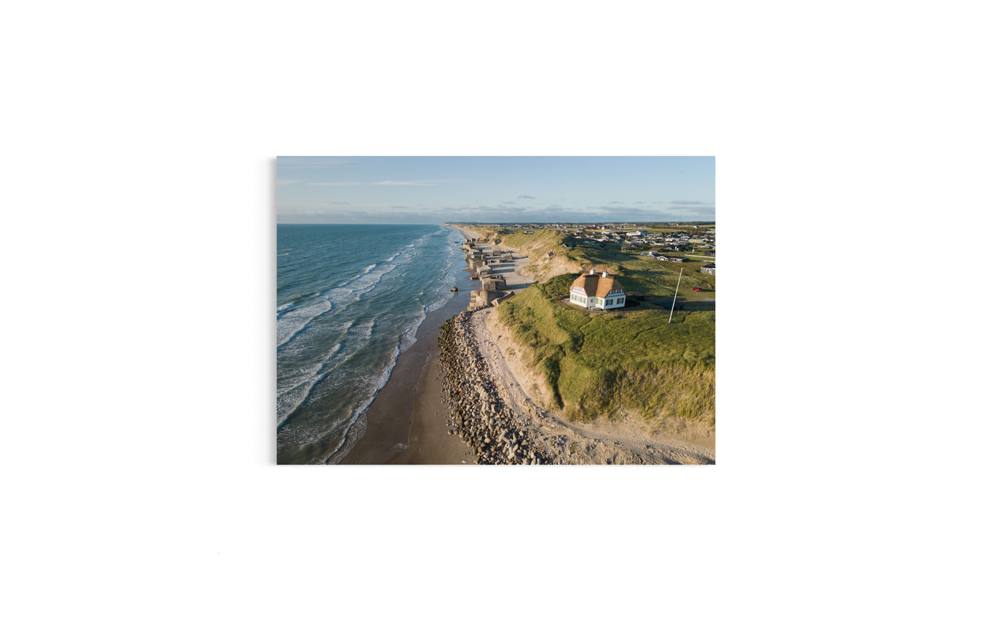 Landskabsbillede af et af Danmarks mest unikke huse på stranden i Løkken i Nordjylland. Dronebillede af landskab, natur og arkitektur trykt som plakat eller på fotolærred til hjemmet