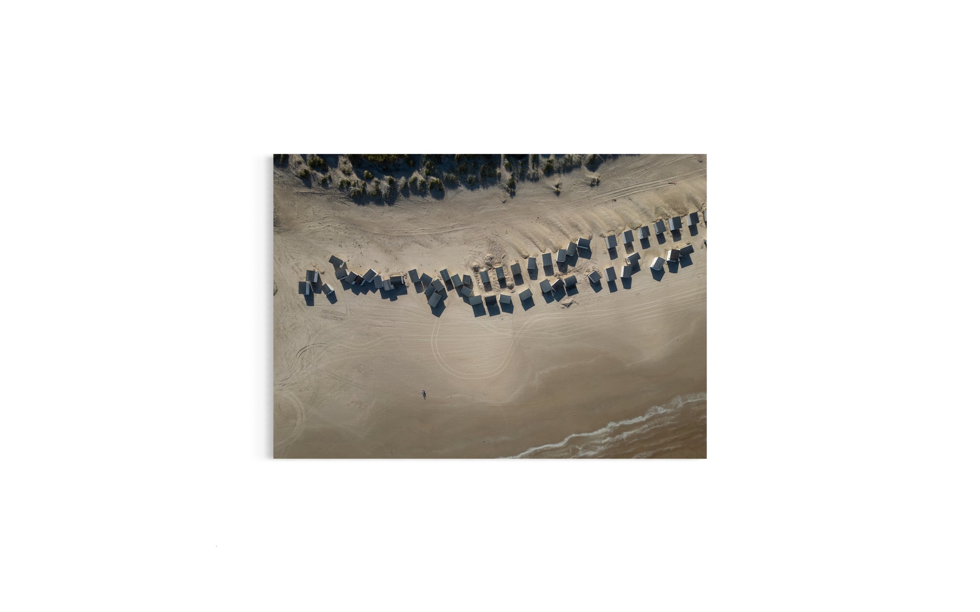 Landskabsbillede taget over badehusene på stranden i Løkken i Nordjylland. Dronebillede af landskab, natur og arkitektur trykt som plakat eller på fotolærred til hjemmet