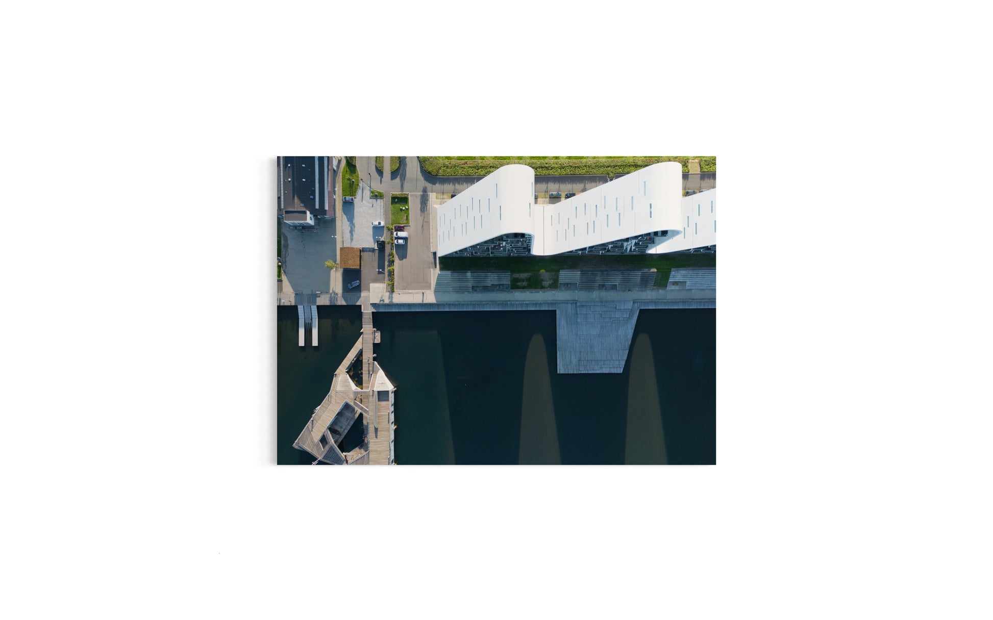 Landskabsbillede af Bølgen i Vejle der kaster sine skygger ud i fjorden. Dronebillede af landskab, natur og arkitektur trykt som plakat eller på fotolærred til hjemmet